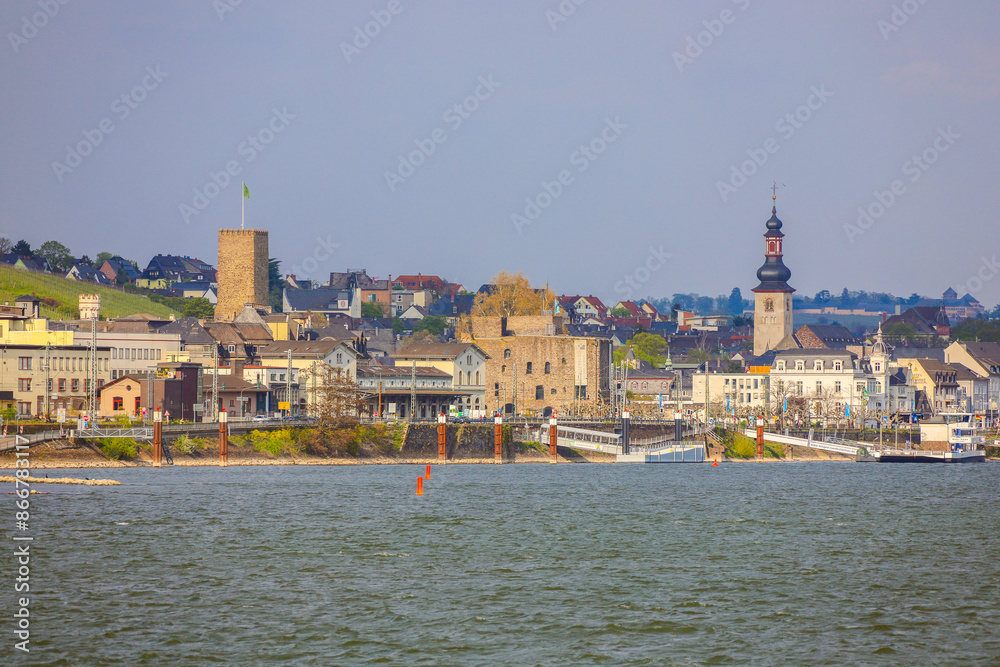 Obraz premium Rüdesheim am Rhein ist eine malerische Stadt, bekannt für ihre historische Altstadt mit charmanten Fachwerkhäusern und der berühmten Drosselgasse, die von Weinlokalen gesäumt ist. Oberhalb der Stadt t