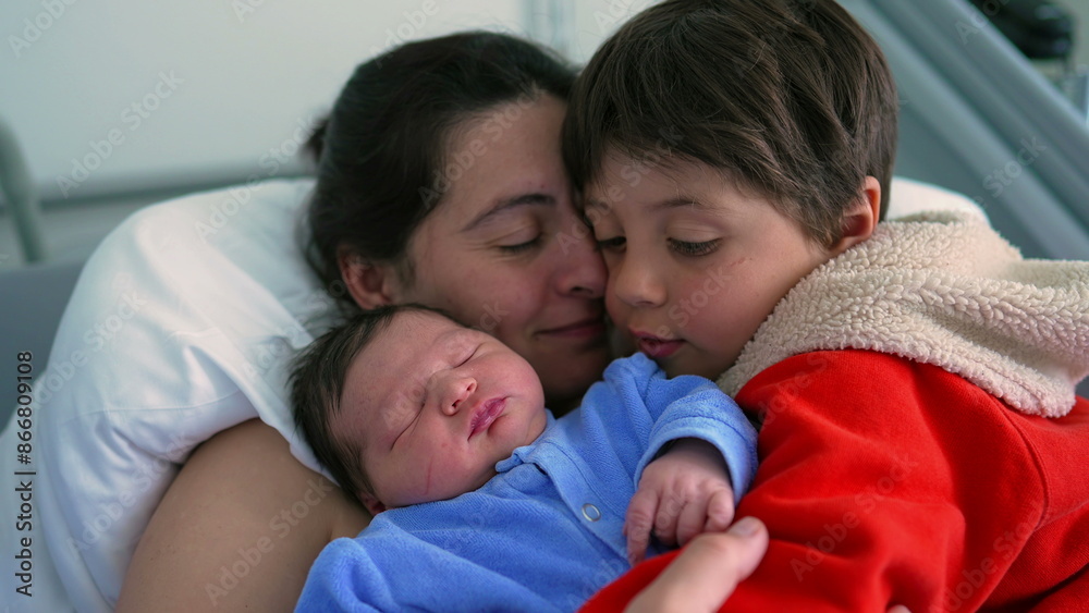 Mother and her children, a newborn and a big brother, sharing a tender family moment in a hospital setting. The image highlights love, warmth, and the bond between siblings Mother and her children, a newborn and a big brother, sharing a tender family moment in a hospital setting. The image highlights love, warmth, and the bond between siblings