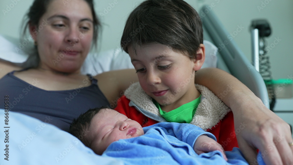 Obraz premium Mother watches lovingly as older sibling cradles newborn baby, highlighting the tender bonds of family love, affection, and the nurturing connection between siblings in a heartfelt moment