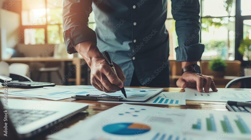 A man focused on writing notes beside detailed graphs.  