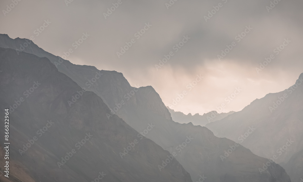 Silhouette of Tien Shan rocky mountain range against cloudy sky in Pamir in Tajikistan mountains, minimalistic abstract landscape of mountains for background Silhouette of Tien Shan rocky mountain range against cloudy sky in Pamir in Tajikistan mountains, minimalistic abstract landscape of mountains for background