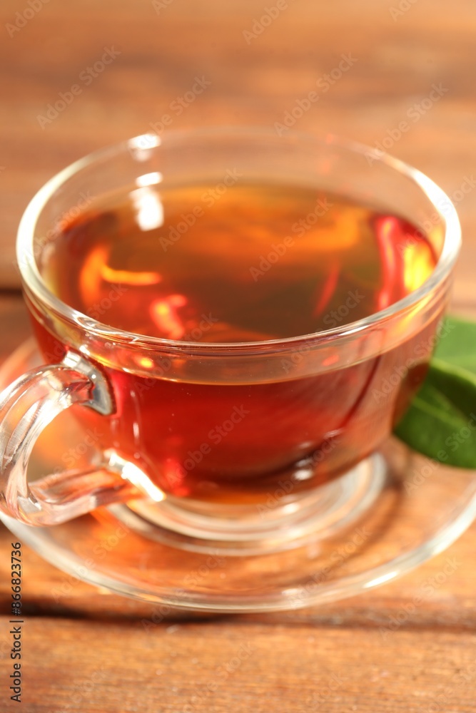 Aromatic tea in glass cup and green leaves on wooden table, closeup Aromatic tea in glass cup and green leaves on wooden table, closeup