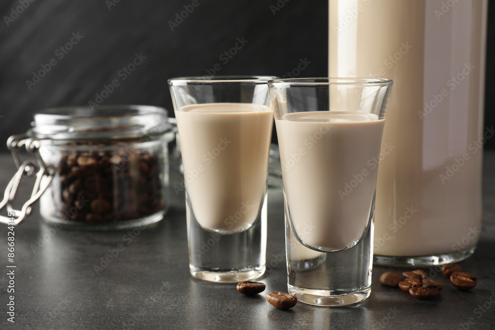 Coffee cream liqueur in glasses, bottle and beans on grey table, closeup Coffee cream liqueur in glasses, bottle and beans on grey table, closeup