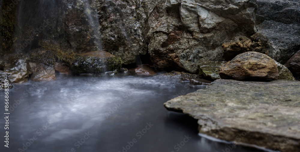 A Blurred Foreground Rock Podium for a Product Display, with Close Detail to a Wet Moss and Stone Background with an Intentional Motion Waterfall. A Blurred Foreground Rock Podium for a Product Display, with Close Detail to a Wet Moss and Stone Background with an Intentional Motion Waterfall.