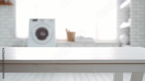Folded towels on countertop with laundry machine in background. White table in front of washing machine with blurring background. Home comfort and modern lifestyle concept for interior design. AIG35.