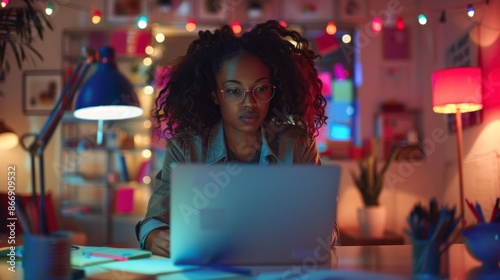 beautiful brunette woman with curly hair working on her laptop in her room photo