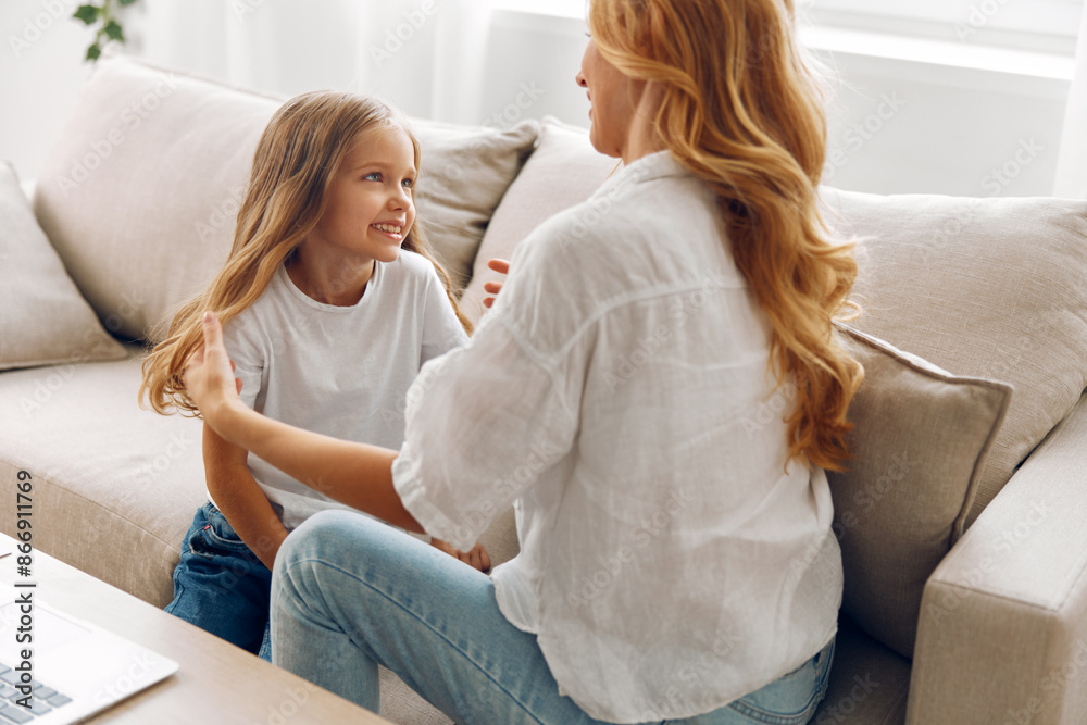 Mother and daughter bonding time enjoying a cozy afternoon together on the couch with a laptop