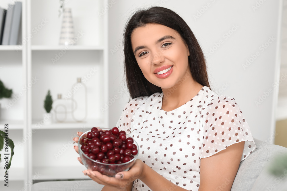 Happy beautiful young woman with bowl of ripe cherries in living room Happy beautiful young woman with bowl of ripe cherries in living room