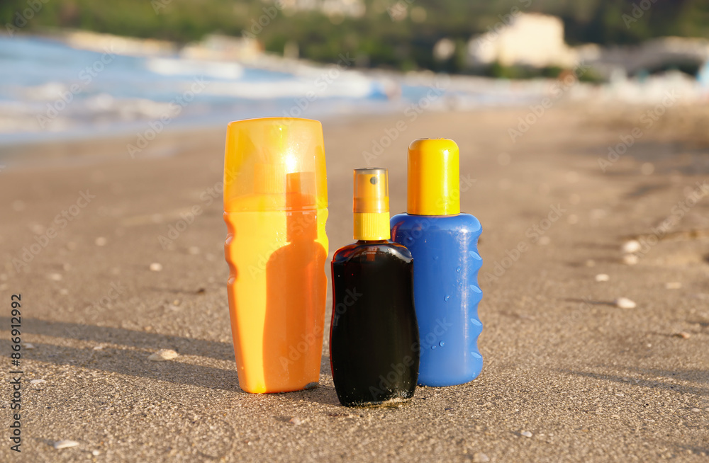 Bottles of sunscreen cream on sand near ocean at beach Bottles of sunscreen cream on sand near ocean at beach