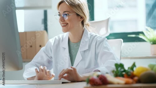 Video of beautiful smart nutritionist woman working with computer while taking notes in the nutritionist consultation