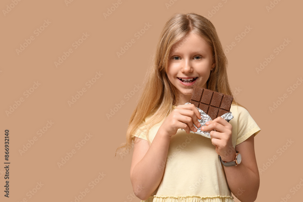 Happy little girl with sweet chocolate bar on brown background Happy little girl with sweet chocolate bar on brown background