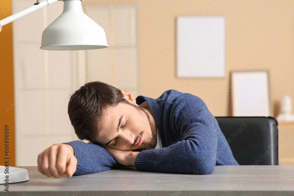 Fototapeta premium Tired young man sleeping at table in office