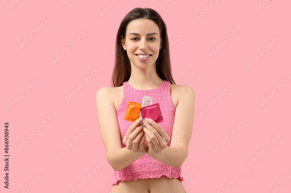 Beautiful young woman with condoms on pink background Beautiful young woman with condoms on pink background