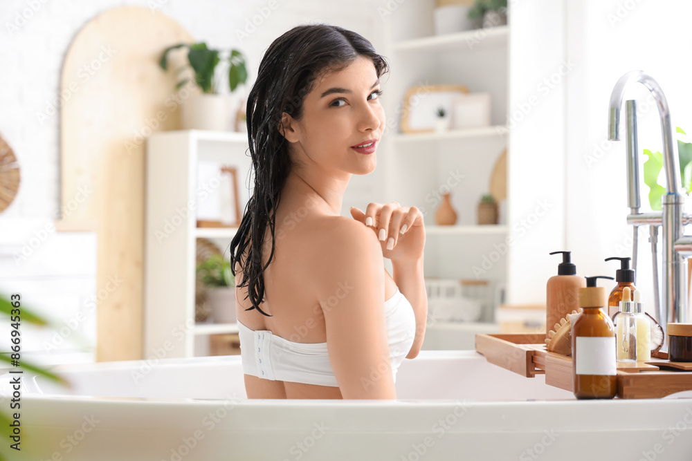 Beautiful young happy woman with bottles of cosmetic products applying hair mask in bathroom at home Beautiful young happy woman with bottles of cosmetic products applying hair mask in bathroom at home