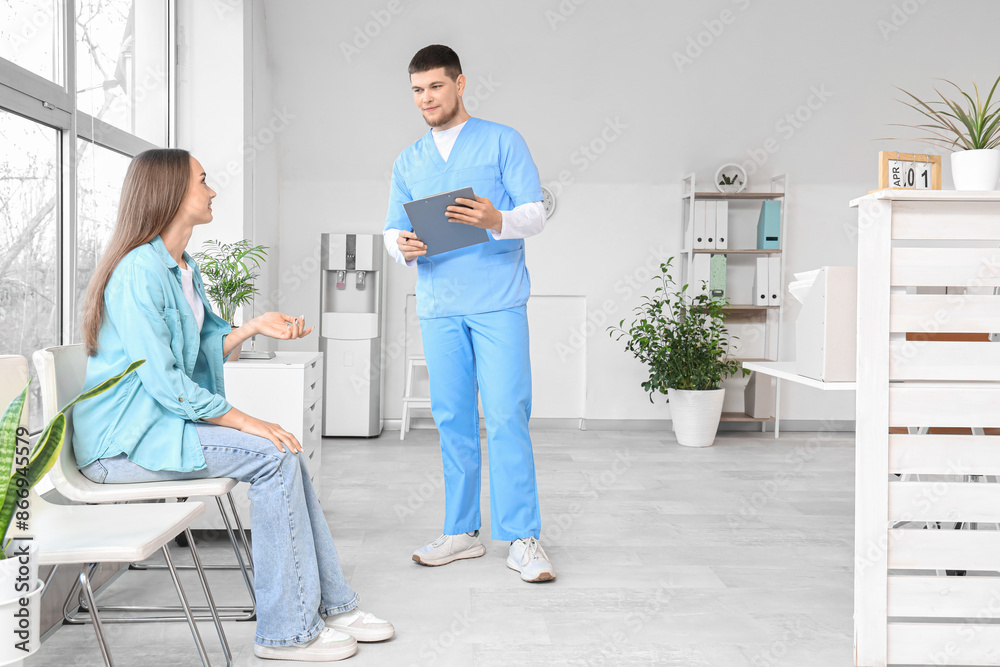 Fototapeta premium Male receptionist with waiting patient in clinic
