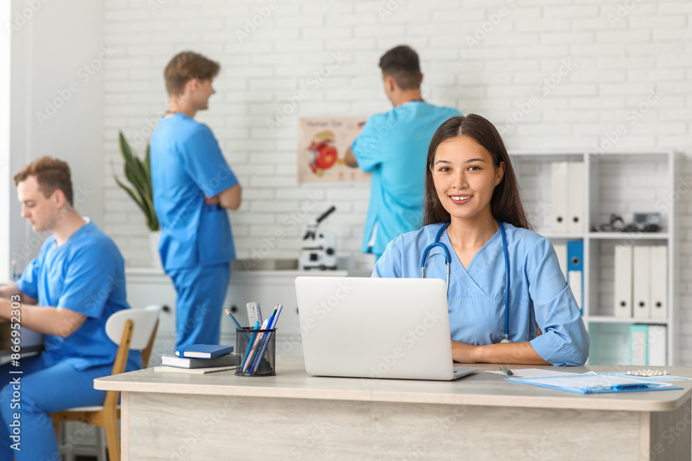 Obraz premium Female Asian doctor working with laptop at table in clinic