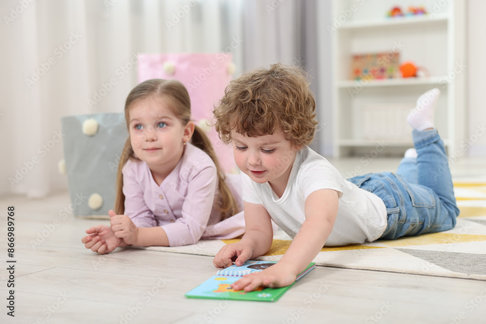 Cute little children reading book on floor in kindergarten Cute little children reading book on floor in kindergarten