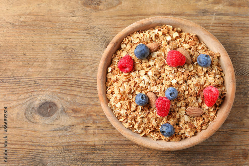 Tasty granola with fresh berries and nuts on wooden table, top view. Space for text Tasty granola with fresh berries and nuts on wooden table, top view. Space for text