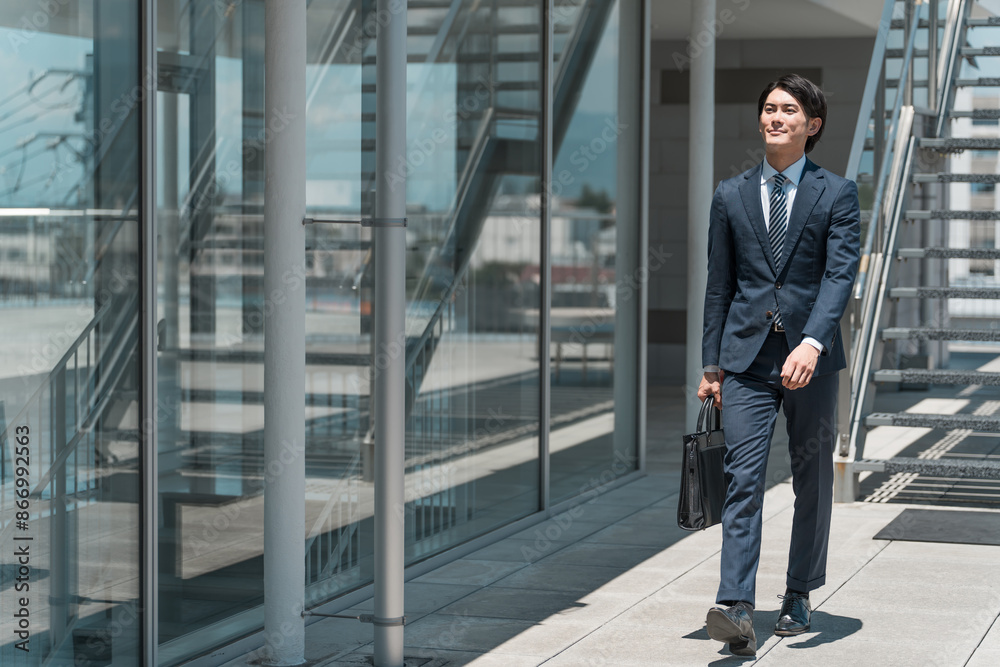 Obraz premium ビジネス街・オフィス街を歩くビジネスマン男性（飛び込み営業・外回り・営業マン・セールスマン） 
