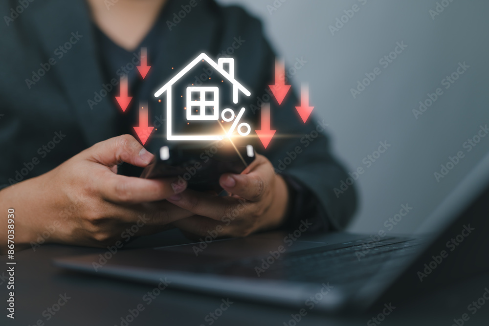 Businessman use smartphone with virtual home icon and down arrow for economical real estate and lower mortgage interest rates. Reduced prices for rental housing, Demand for home purchases decreases. Businessman use smartphone with virtual home icon and down arrow for economical real estate and lower mortgage interest rates. Reduced prices for rental housing, Demand for home purchases decreases.