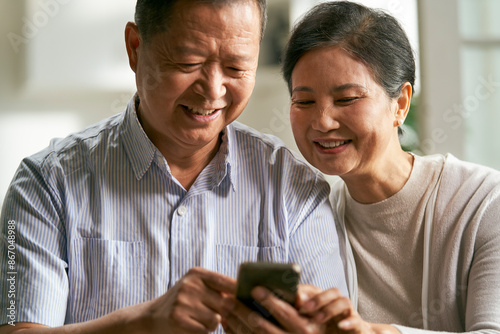 Photography senior asian couple using cellphone together at home