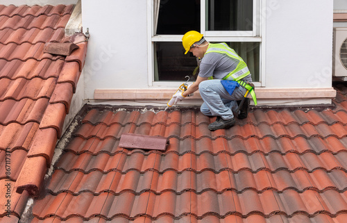 Construction worker using silicone sealant adhesive to fix crack of the old tile roof. © toa555