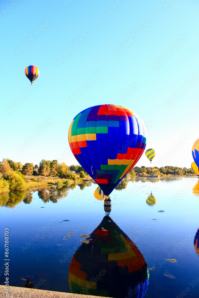 Obraz premium Dawn ascent of vibrant balloons over water