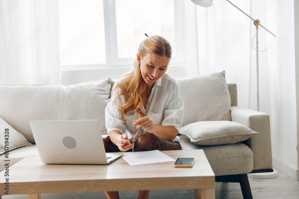 Woman on couch working remotely with laptop and pen, engaged in creative or professional task Woman on couch working remotely with laptop and pen, engaged in creative or professional task