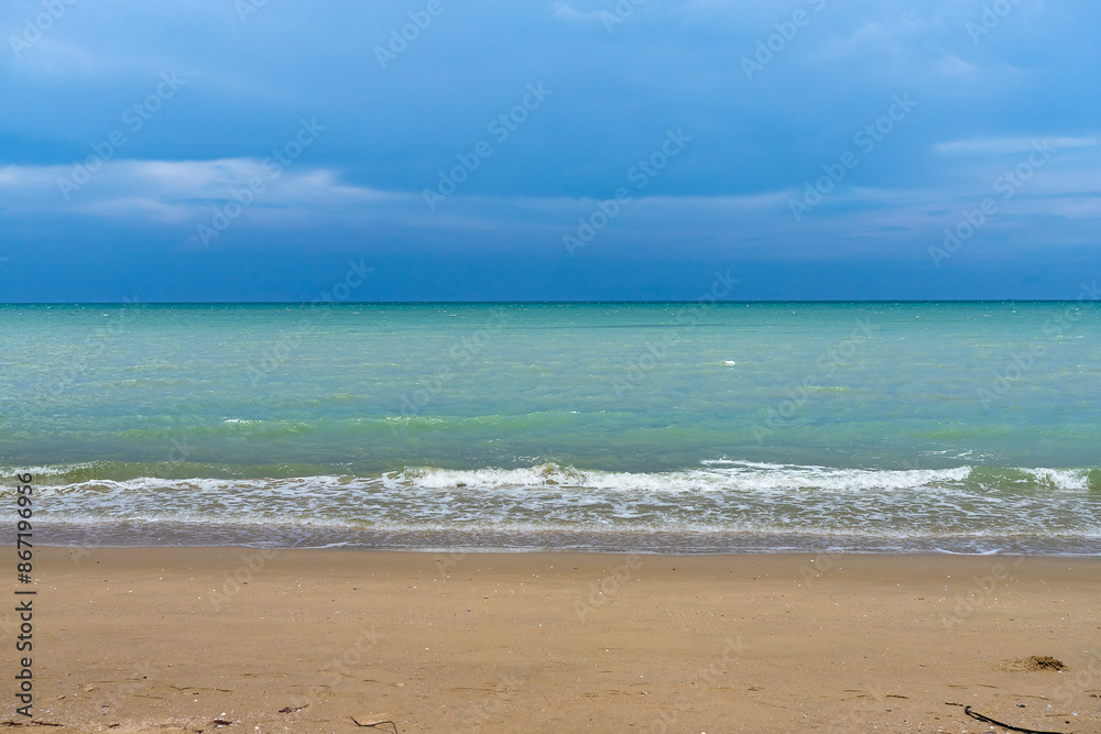Fluffy clouds drift across a bright summer sky above a tropical beach with turquoise waves lapping at the shore Fluffy clouds drift across a bright summer sky above a tropical beach with turquoise waves lapping at the shore