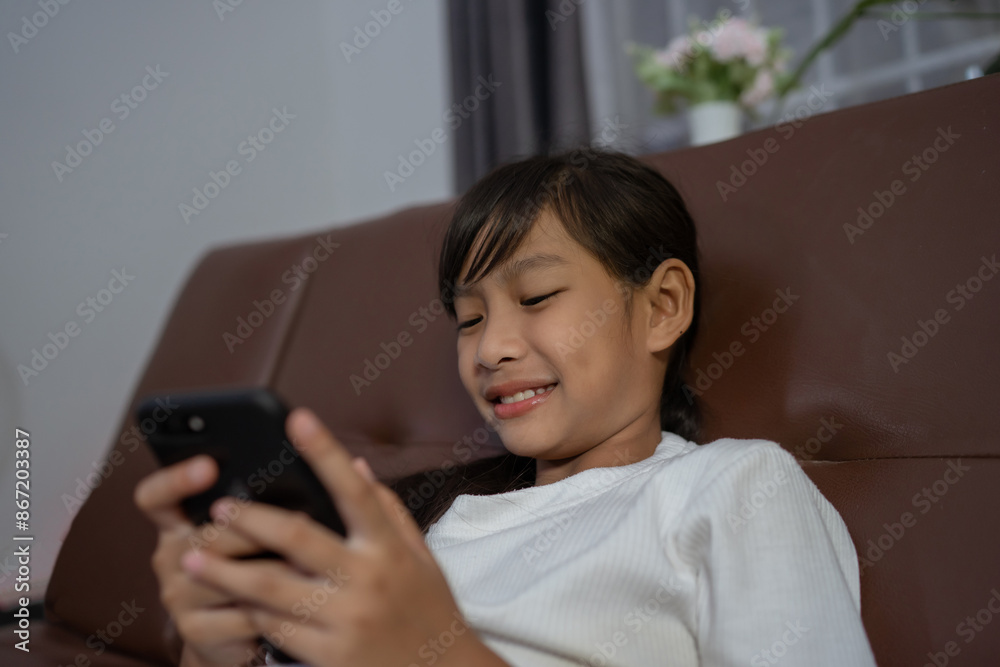 Happy young asian little girl relaxing at home.texting messaging on smartphone, smiling little girl use cellphone, chatting online message. Happy young asian little girl relaxing at home.texting messaging on smartphone, smiling little girl use cellphone, chatting online message.