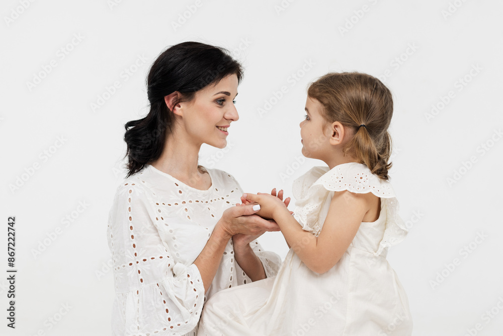 Family relationship between mother and daughter. Loving mother with her little daughter on a light studio background. Tender moment, family support. Family relationship between mother and daughter. Loving mother with her little daughter on a light studio background. Tender moment, family support.