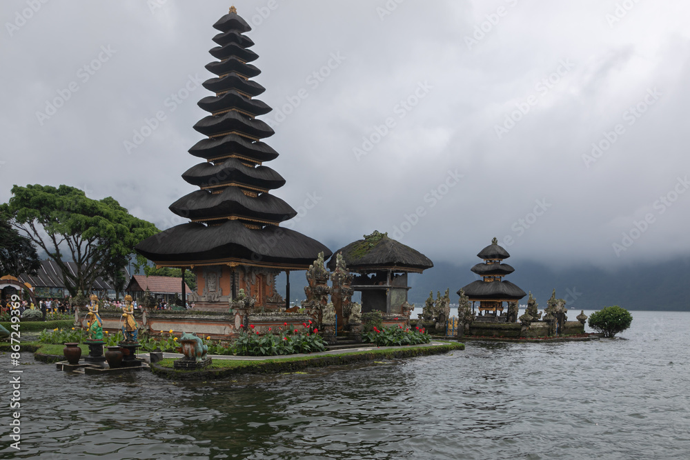 Pura Oolong Danu Bro Bedugul is a Hindu temple on the Indonesian island of Bali. Sacred building is on the shore of Lake Beratan. Mystical fog around, mountains with a tropical forest in the distance Pura Oolong Danu Bro Bedugul is a Hindu temple on the Indonesian island of Bali. Sacred building is on the shore of Lake Beratan. Mystical fog around, mountains with a tropical forest in the distance