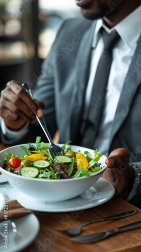 Close-up of a man in a suit eating a salad © Salsabila Ariadina