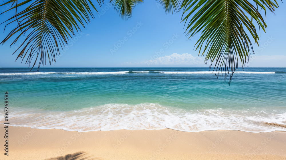 Golden sandy beach with turquoise ocean waves under clear blue sky, framed by palm tree leaves Golden sandy beach with turquoise ocean waves under clear blue sky, framed by palm tree leaves