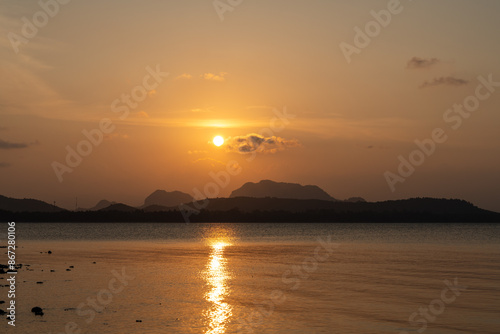 The sunset over the calm sea with reflections reflecting the beauty of nature. In the atmosphere of brown and yellow light, it is very beautiful.