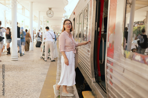 City travel and solo tourism concept. Tourist woman enters a train carriage at the transport station. Copy space. Part of the series. © Forewer