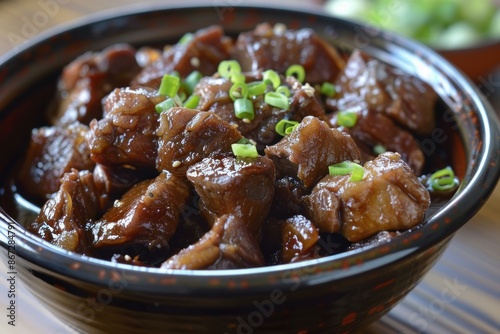 Bowl filled with appetizing braised beef, seasoned and garnished with fresh green onions