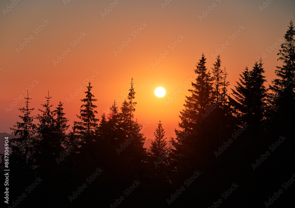 Orange sunrise over coniferous forest. Warm light of mountain dawn. Stunning landscape of sunrise in mountains. Orange sunrise over coniferous forest. Warm light of mountain dawn. Stunning landscape of sunrise in mountains.