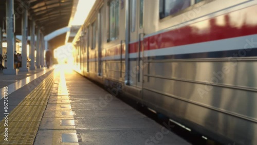 A commuterline electric train car is running in the morning with many passengers waiting by the rail, yellowish sunlight in the distance photo