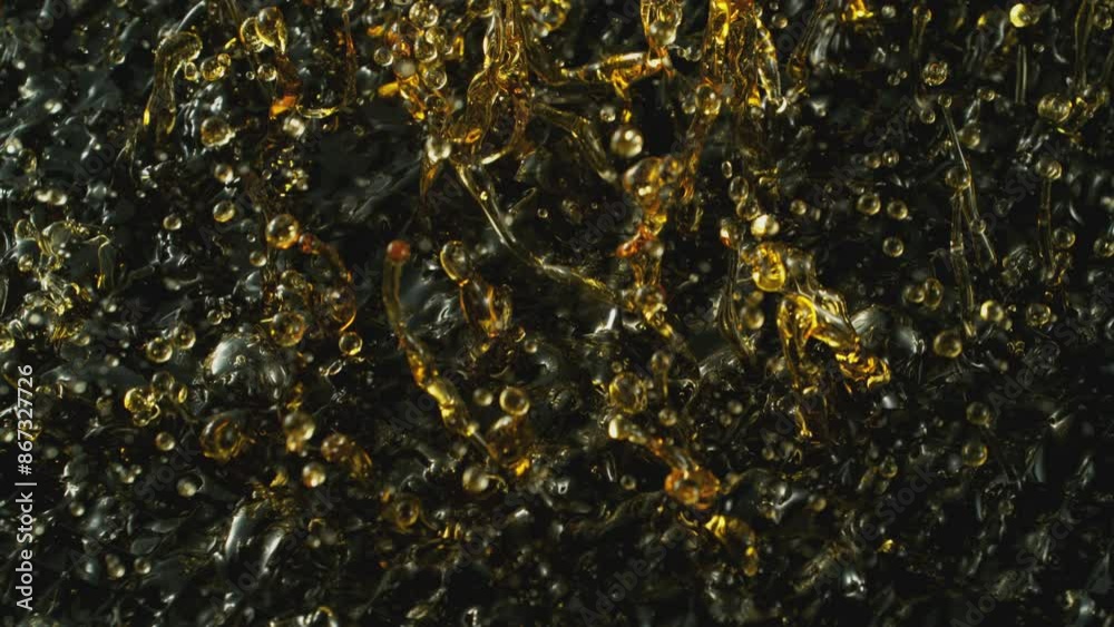 Super Slow Motion of Splashing Oil Waves on Black Background. Filmed on High Speed Cinema Camera, 1000fps. Abstract Golden Oil Splashes, Beauty or Cooking Concept. Super Slow Motion of Splashing Oil Waves on Black Background. Filmed on High Speed Cinema Camera, 1000fps. Abstract Golden Oil Splashes, Beauty or Cooking Concept.