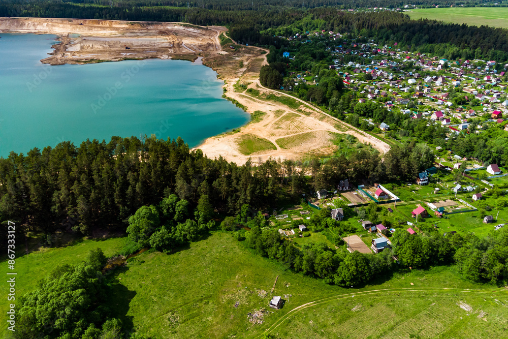 Aerial view of a settlement next to a lake formed on the site of a sand quarry, beautiful countryside landscape Aerial view of a settlement next to a lake formed on the site of a sand quarry, beautiful countryside landscape