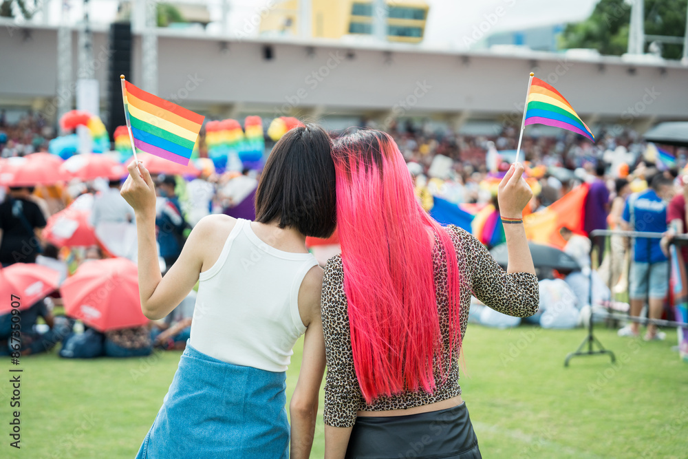 Fototapeta premium Celebrate in pride month festival. Pride movement transgender asian couple lesbian LGBT holding rainbow flag for freedom. Gatherings of friends in parade communities celebrating LGBTQ+ causes.
