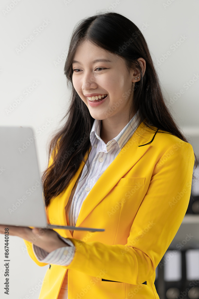Attractive Asian woman sitting on laptop computer in business office Calculate balances, documents, and check income within the company. vertical picture Attractive Asian woman sitting on laptop computer in business office Calculate balances, documents, and check income within the company. vertical picture