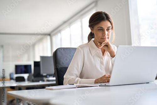 Mature 45 years old professional business woman executive working on computer technology in office, busy middle aged businesswoman hr manager using laptop sitting at work desk. Copy space for ads.