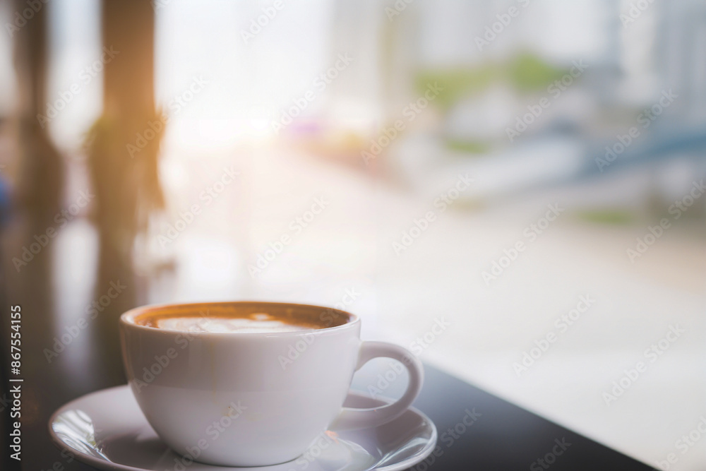Cup of hot coffee on the table with coffee shop or cafe background in the morning Cup of hot coffee on the table with coffee shop or cafe background in the morning