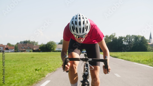 Young female professional bicyclist during road cycling sprint, continual motion with maximal effort, close-up view. photo