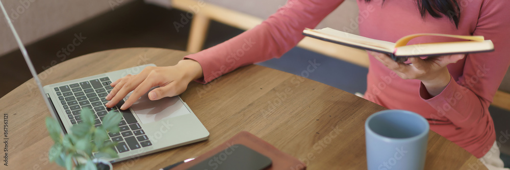 Young businesswoman working at home to searching business data on laptop and checking in notebook Young businesswoman working at home to searching business data on laptop and checking in notebook