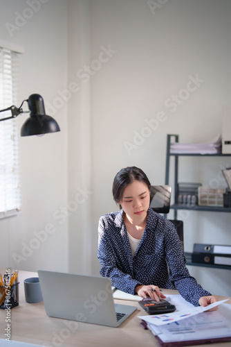 Businesswoman reading finance document and checking statistics with calculator to thinking about investment of business project while working and analysis about strategy marketing of new business