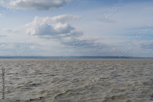 Über dem aufgewühlten Neusiedler See hängen Wolken an diesem Frühlingstag in Illmitz. Das Wasser sieht braun aus, weil darin viele Sedimente gelöst sind.  photo