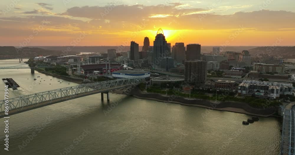 Highway traffic on bridge in Cincinnati, Ohio with illuminated skyscraper buildings in downtown district. American city with business financial district at sunset Highway traffic on bridge in Cincinnati, Ohio with illuminated skyscraper buildings in downtown district. American city with business financial district at sunset
